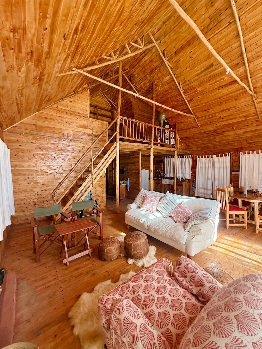Vaulted timber interior of the chalet with loft, hand-hewn beams and a sunlit reading nook